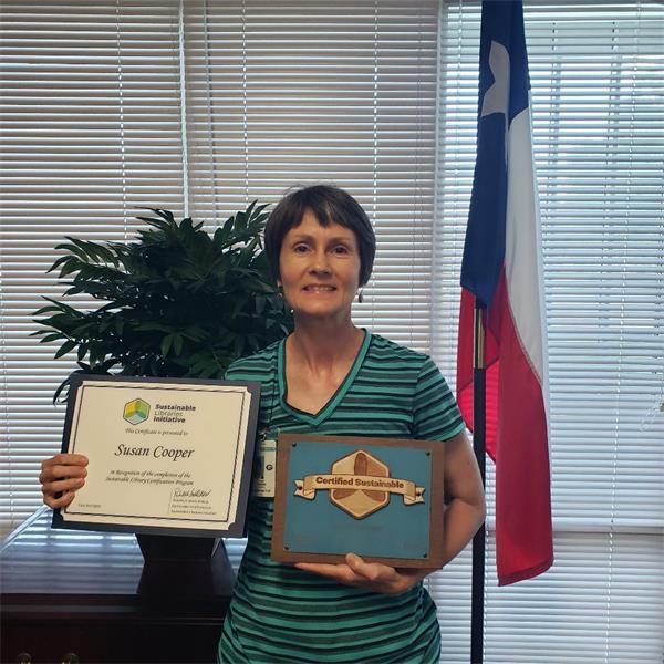School Librarian, Susan Cooper holding her Certificate and Plaque she received for completing the Sustainable Library Certification Program